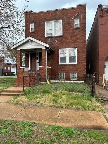 Saint Louis apartment for rent - the front of a brick house with grass and a fence