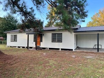 Deridder house for rent - a white house with a porch and a tree in front of it