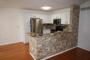 Shelby Township house for rent - a kitchen with a stone wall and a stainless steel refrigerator