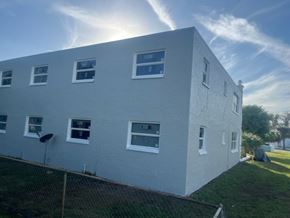 Fort Myers apartment for rent - A white building with multiple windows and a fence in front.