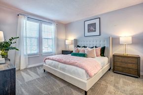 Daytona Beach apartment for rent - A bedroom with a large bed, a nightstand, and a plant.