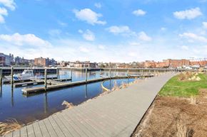 Greenwich apartment for rent - A walkway runs parallel to a body of water with buildings in the background.