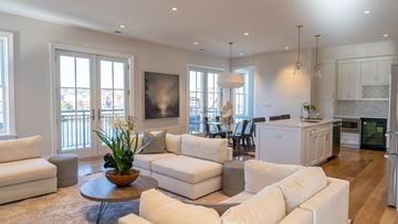 Greenwich apartment for rent - A modern living room with white furniture and a large window.