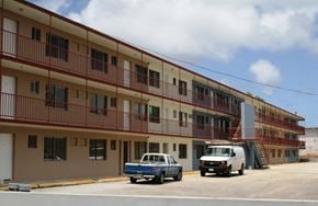 Tamuning apartment for rent - a building with trucks parked in front of it