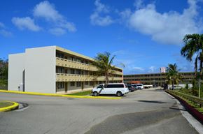 Tamuning apartment for rent - a building with cars parked in front of it and palm trees