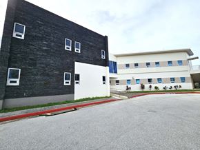 Tamuning apartment for rent - A black building with white windows is adjacent to a white building with blue trim.