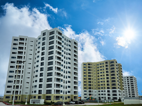 Tamuning apartment for rent - A large white building with a lot of windows is in the foreground.
