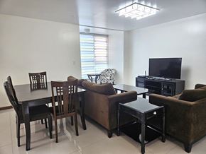 Tamuning apartment for rent - A living room with a brown couch, a black table, and a television.