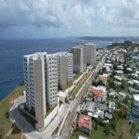 Tamuning apartment for rent - A row of white buildings are situated on a hillside overlooking the ocean.