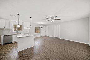 Houston house for rent - an empty living room with a kitchen and a ceiling fan