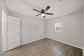 Houston house for rent - an empty bedroom with a ceiling fan and a window