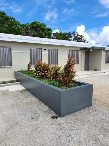 Yigo apartment for rent - a large concrete planter with tropical plants in front of a building