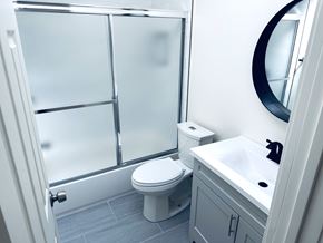 Los Angeles apartment for rent - A white toilet is in a bathroom with a white sink and a round mirror.