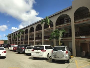 Tumon apartment for rent - a parking lot full of cars in front of a building