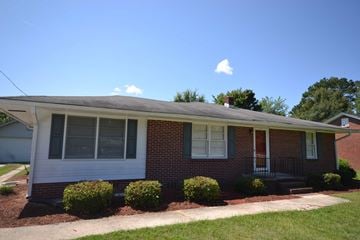 Florence house for rent - the front of a brick house with a porch and some bushes