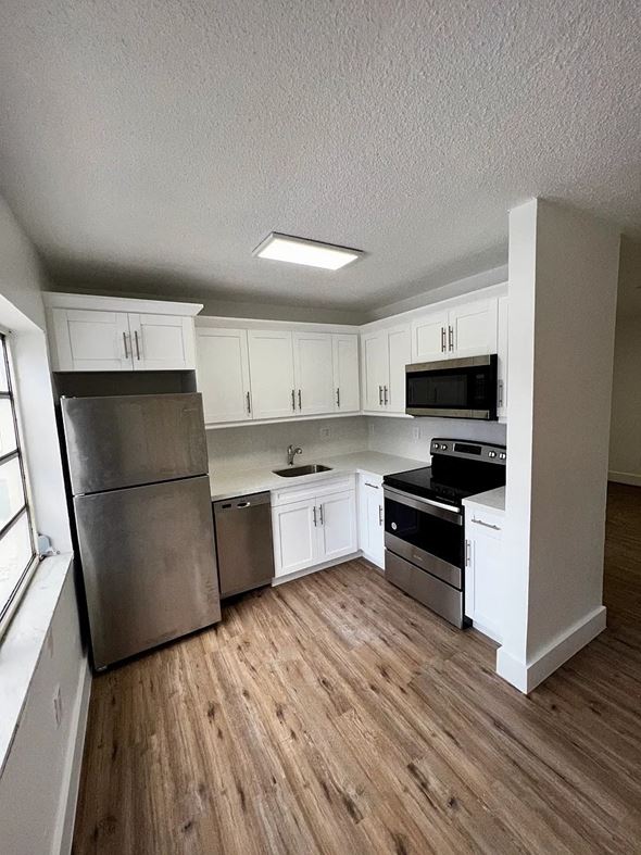 Miami apartment for rent - A kitchen with white cabinets and a wooden floor.
