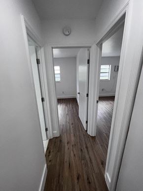 Miami apartment for rent - A long hallway with white walls and wood floors.