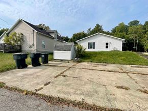 New Albany apartment for rent - A white house with a grey roof is situated in a grassy area with a concrete driveway in front.
