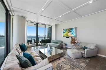 Miami apartment for rent - A modern living room with a large window overlooking the water.