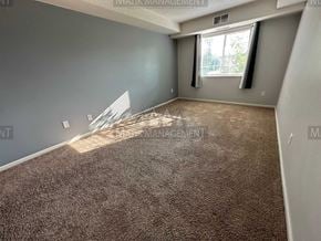 Rochester apartment for rent - a carpeted living room with a window and gray walls