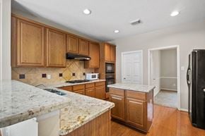 Rosharon house for rent - A kitchen with wooden cabinets and granite countertops.