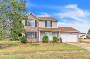Louisville house for rent - a brick house with a white garage door and a lawn