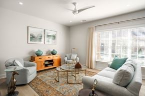 Aiken apartment for rent - A living room with a grey couch, a wooden coffee table, and a ceiling fan.