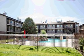 Orem apartment for rent - an apartment building with a pool behind a fence