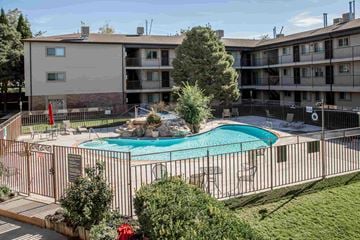 Orem apartment for rent - an apartment building with a swimming pool behind a wrought iron fence