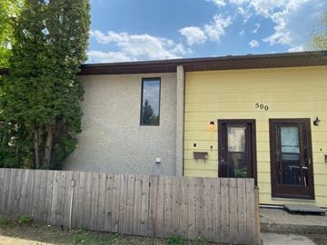 Prince Albert house for rent - the front of a yellow house with a wooden fence
