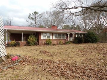 Rome house for rent - A house with a red roof and white trim is surrounded by trees and a white fence.