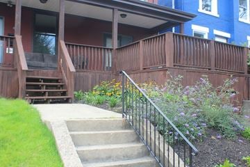 Pittsburgh apartment for rent - A wooden deck with a metal railing and steps leading up to a house.