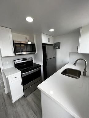 Miami apartment for rent - A modern kitchen with white countertops and stainless steel appliances.