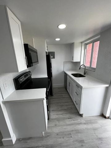 Miami apartment for rent - A kitchen with white cabinets and a black stove top oven.