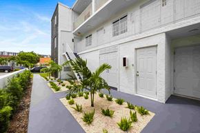 Miami apartment for rent - A white building with a small garden in front.