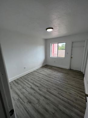 Miami apartment for rent - A room with wooden flooring and a window with red curtains.