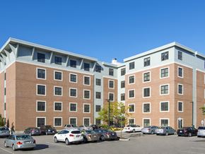 West Roxbury apartment for rent - a large brick building with cars parked in a parking lot