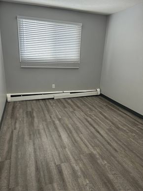 Edmonton apartment for rent - A room with a window covered by blinds and a radiator on the wall.