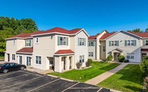 Oshkosh townhouse for rent - A building with a red roof and white walls with a car parked in front.