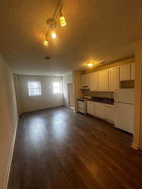 Philadelphia apartment for rent - an empty living room and kitchen with wood floors and white cabinets