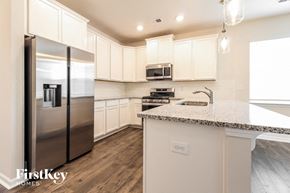 Greenville house for rent - a kitchen with white cabinets and stainless steel refrigerator