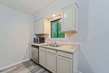 Jacksonville house for rent - a kitchen with white cabinets and a sink and a window