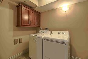 Inglewood apartment for rent - a full size washer and dryer in a laundry room with wooden cabinets