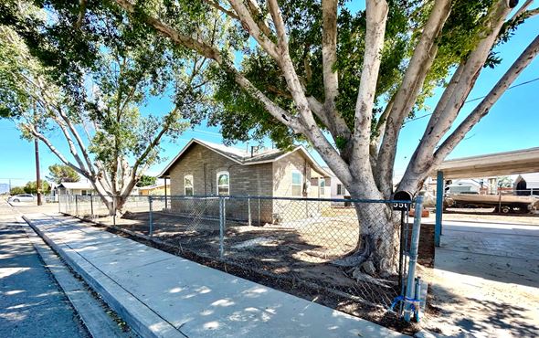 Blythe house for rent - a house behind a chain link fence and a tree