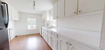 Whiteville house for rent - a large white kitchen with white cabinets and wood floors