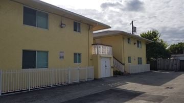 Hallandale Beach apartment for rent - A yellow building with a white fence in front.