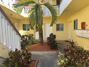 Hallandale Beach apartment for rent - A small courtyard with a palm tree and bushes.