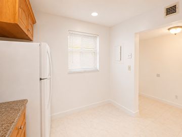Hallandale Beach apartment for rent - A kitchen with a white refrigerator and a window with blinds.