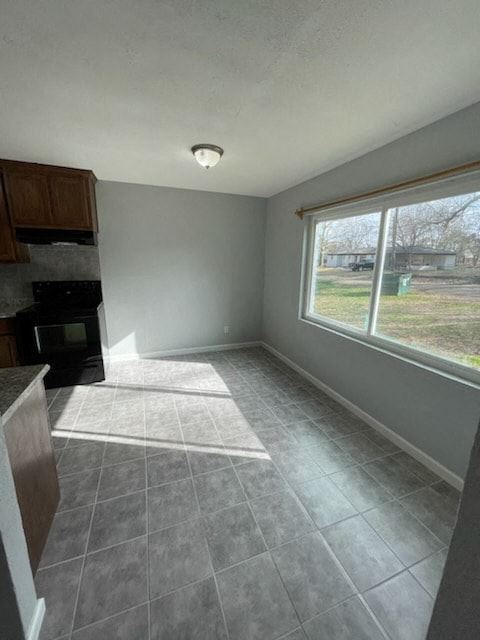 Hughes Springs house for rent - A kitchen with a black stove and a window overlooking a yard.