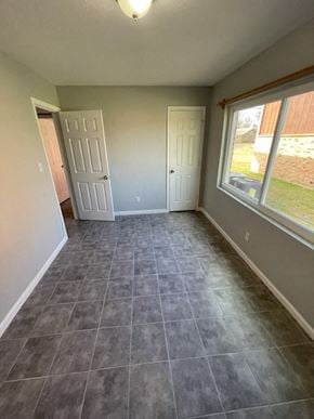 Hughes Springs house for rent - A room with grey tiled flooring and two white doors.